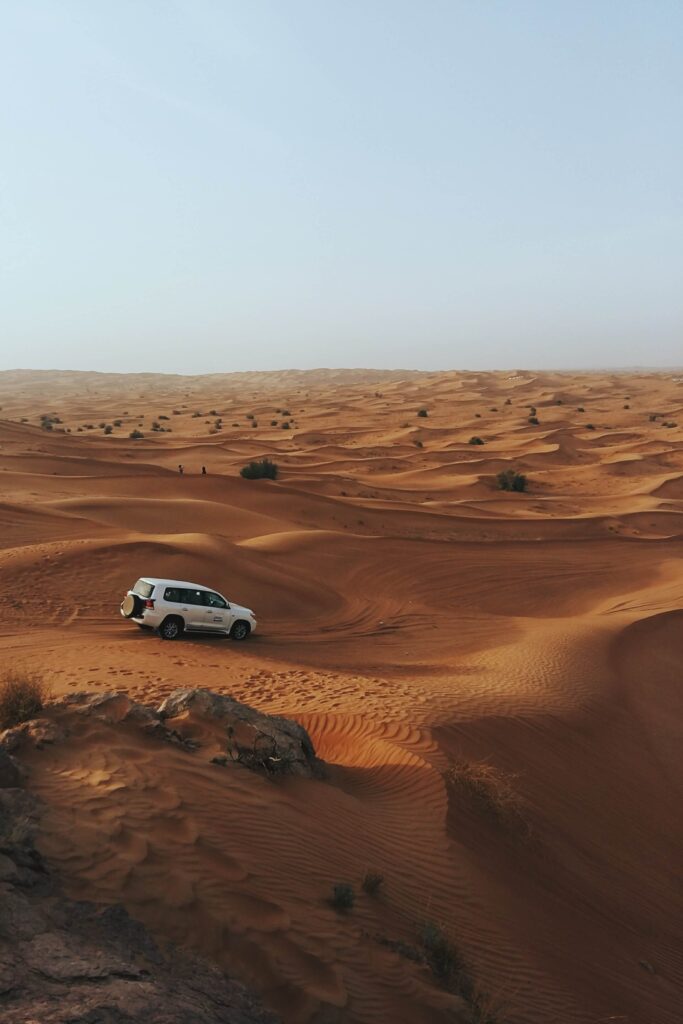 Weisser Jeep fährt durch die Wüste Dubais